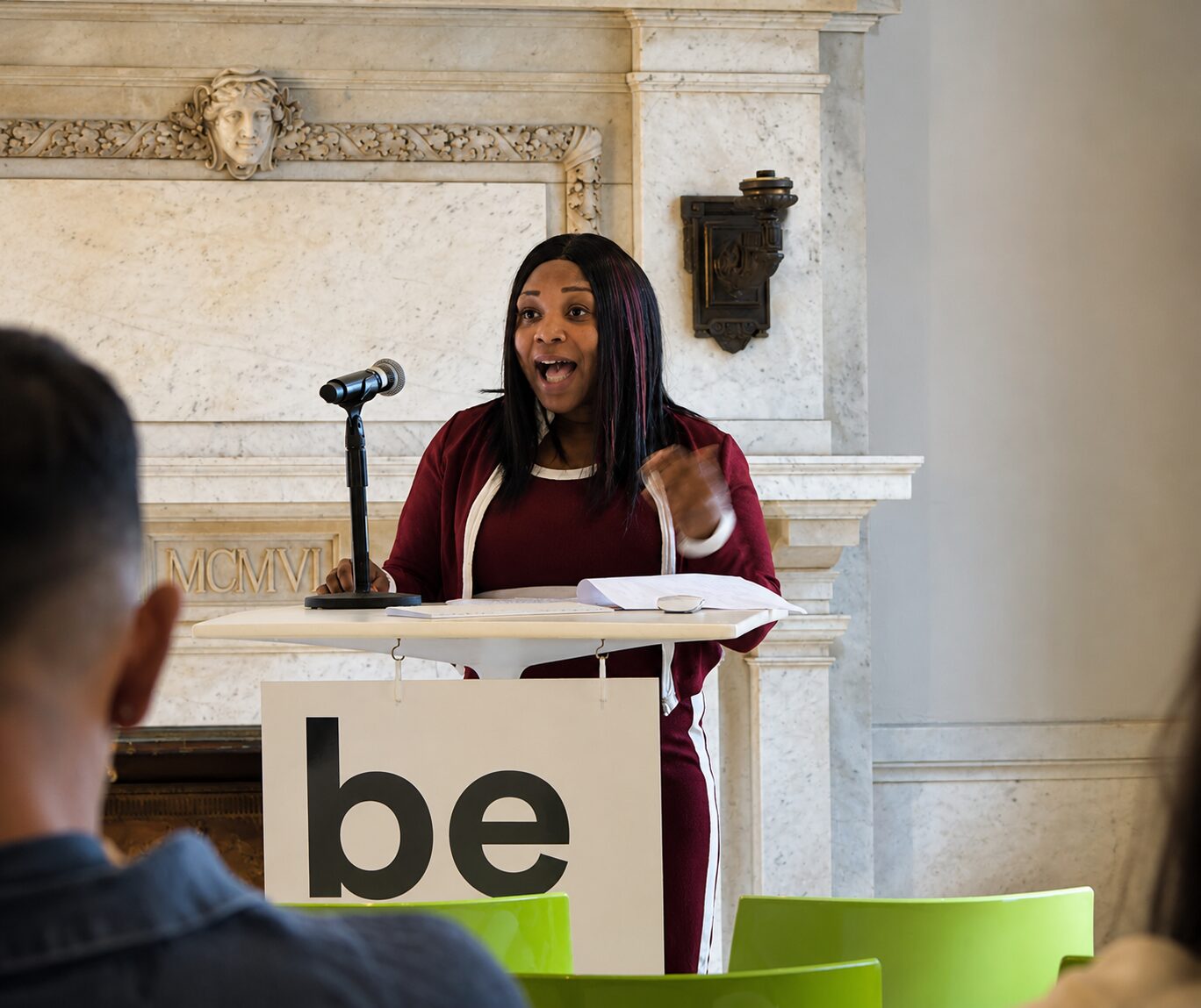 The founder of Next Step Strategies speaking at a podium with a microphone during an event.